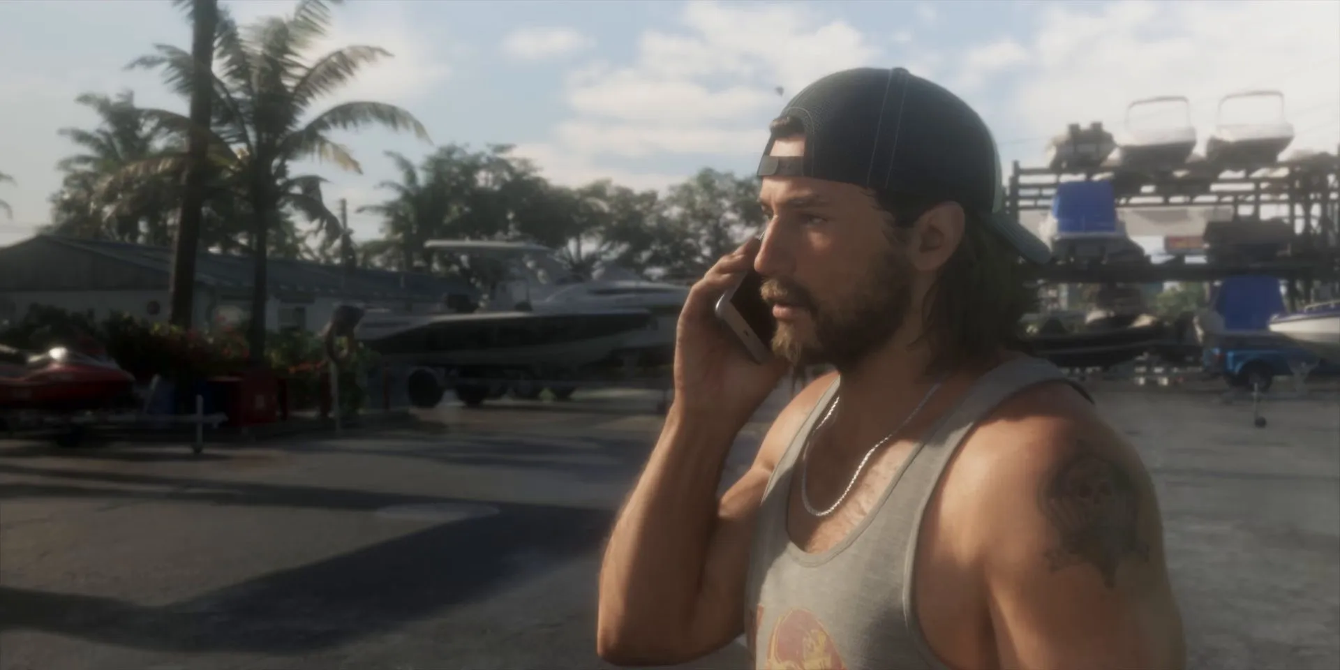 Jason in a backwards cap and tank top takes a phone call from Lucia in a boatyard