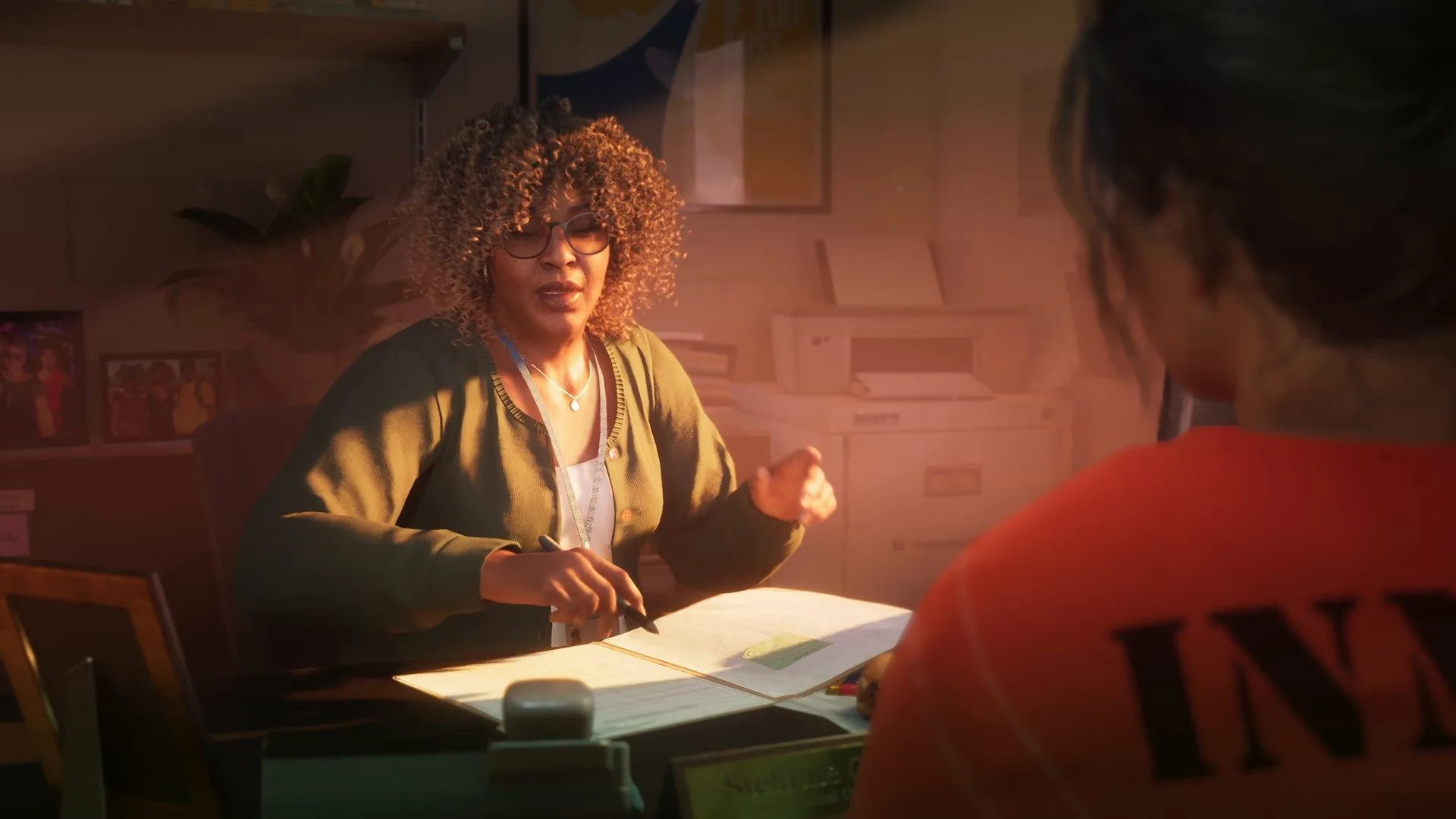 Lucia in an orange inmate jumpsuit faces a curly-haired woman at an interview desk