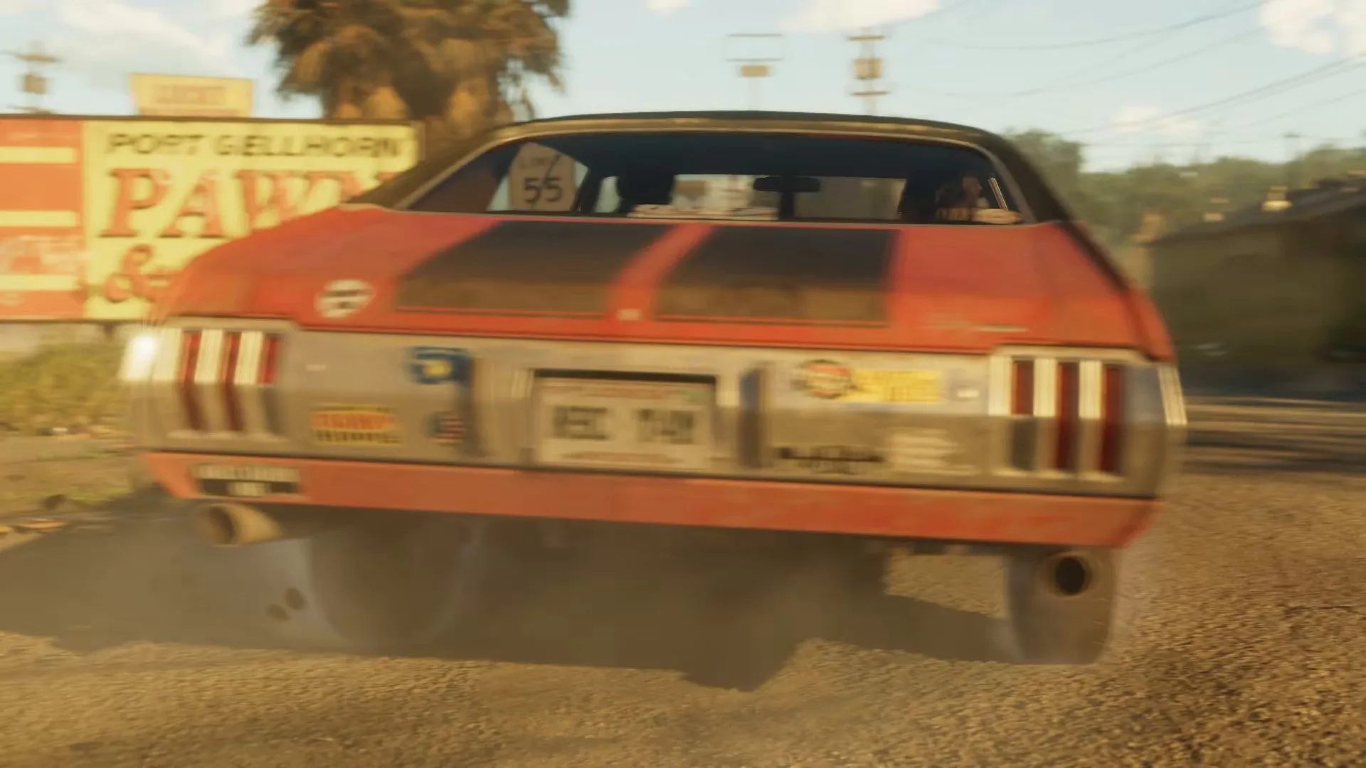 The rear of an orange muscle car passes a Port Gellhorn sign on a dusty road