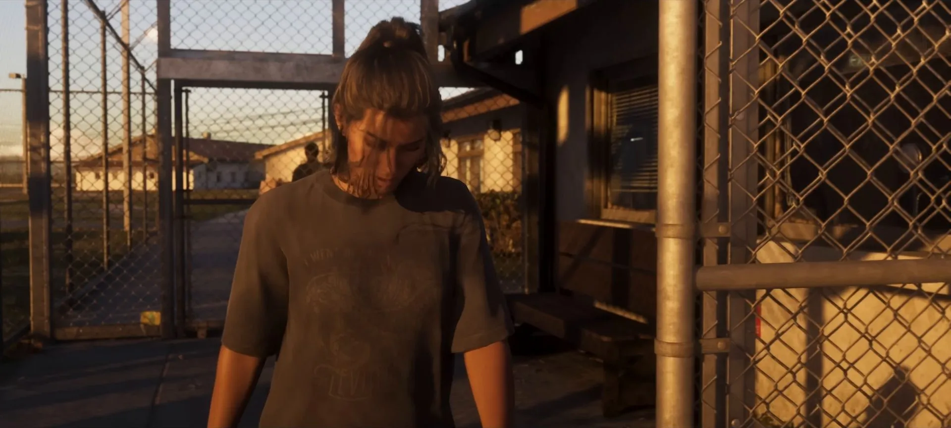 Lucia in a grey T-shirt smiles at a chain-link prison gate as she walks out