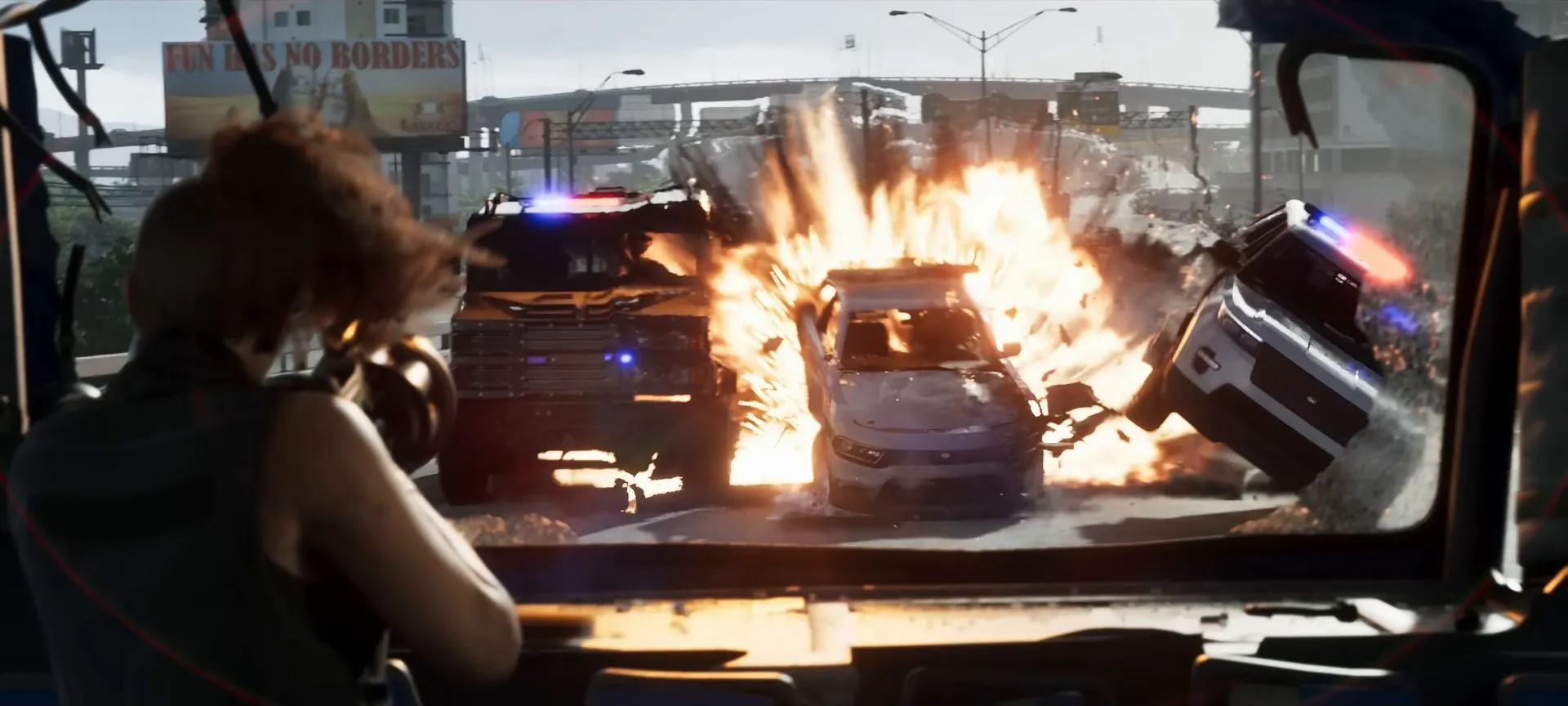 A woman in a truck cab watches police cars explode through a broken windshield